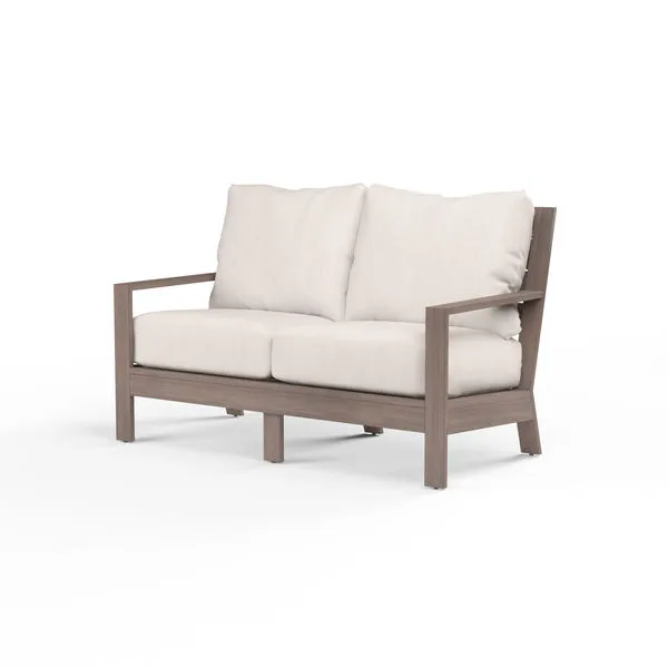 Laguna Loveseat outdoor sofa with hand-brushed aluminum frame mimicking driftwood, featuring white cushions