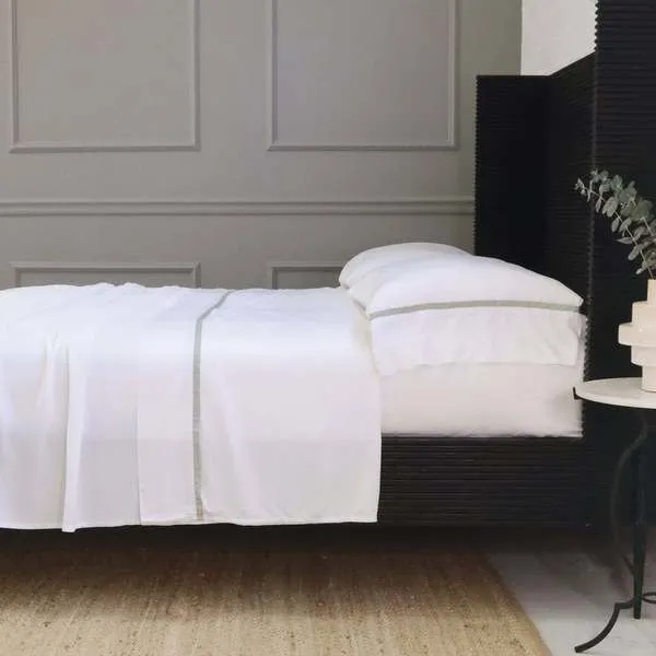 Langston Bamboo Sateen Twin sheet set in crisp white with subtle stitched border on bed in minimal room