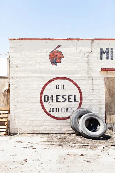 Aerial shot of a high desert Route 66 wall with red Indian head, diesel additives lettering, and tires leaning against whi...