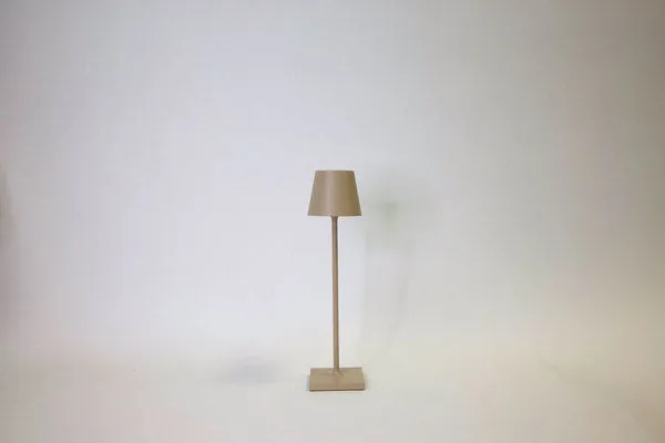 Vera Sand Poldina Pro Table Lamp with a tall, slim sand-colored metal base and matching tapered lampshade
