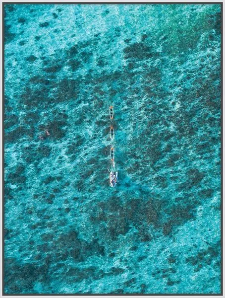 Aerial photograph showing a small boat drifting in vast, turquoise, textured ocean waters conveying solitude and adventure.