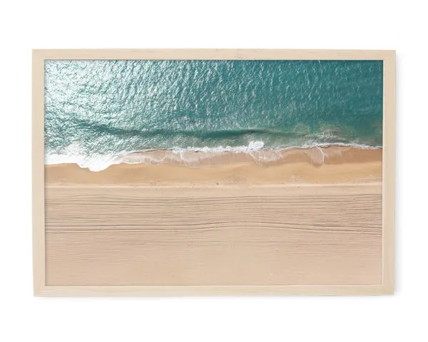 Framed aerial ocean photography with blue waves meeting sandy beach featuring detailed water texture and sand patterns