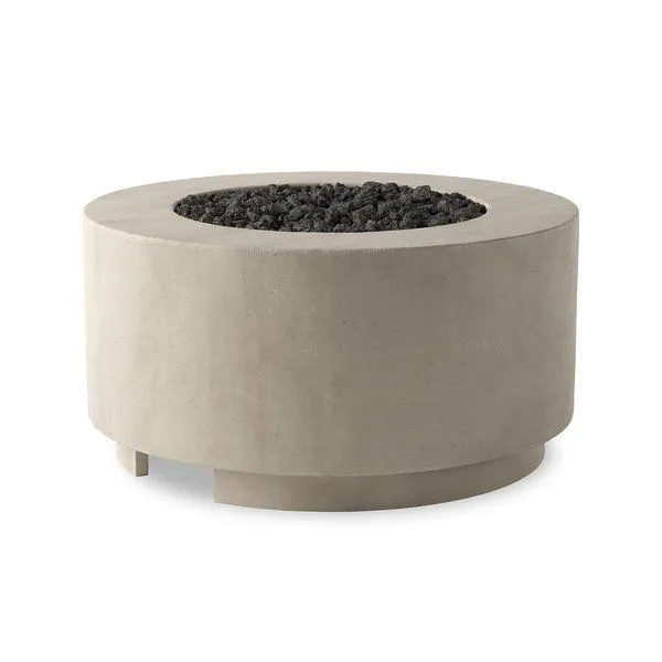 Round outdoor fire table in natural concrete with a wide top and center filled with black lava stones