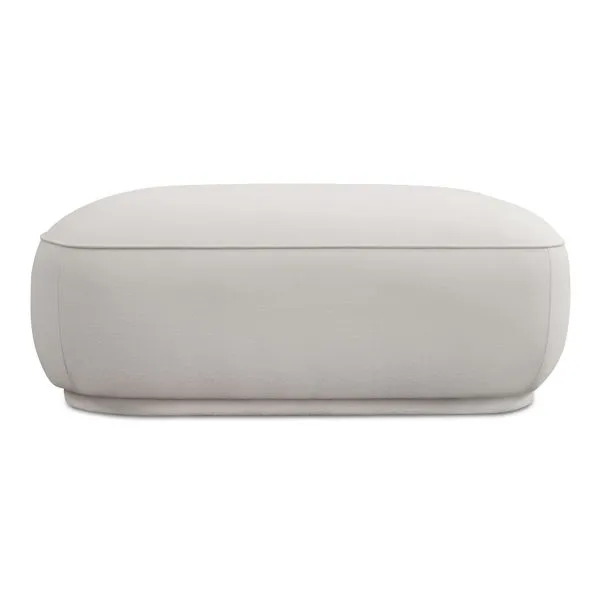 Marion Square Ottoman in light neutral fabric with plump curved sides, detailed piping, and recessed floating base