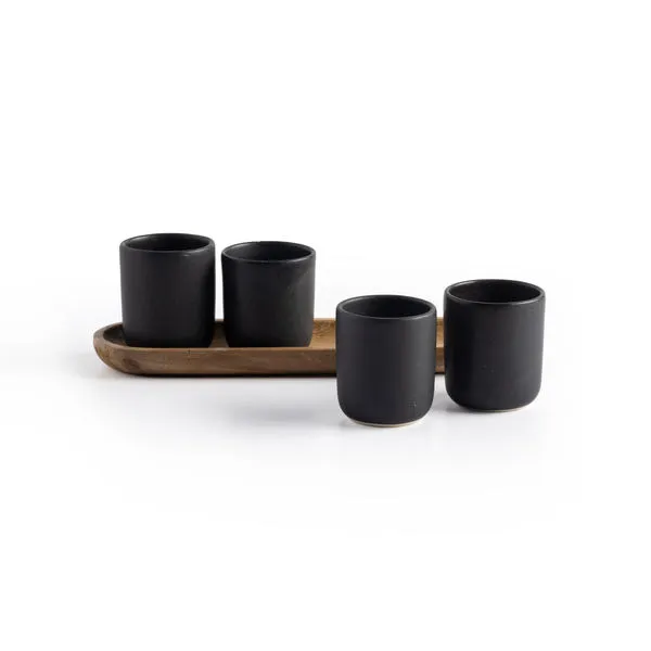 Set of four matte black espresso cups on a natural wooden tray with a smooth, rounded silhouette