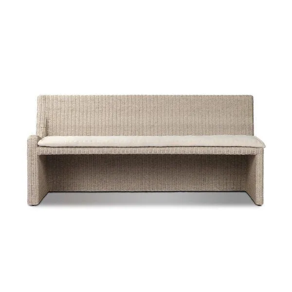 Vintage white outdoor dining banquette with woven rattan texture and a soft beige fabric seat cushion