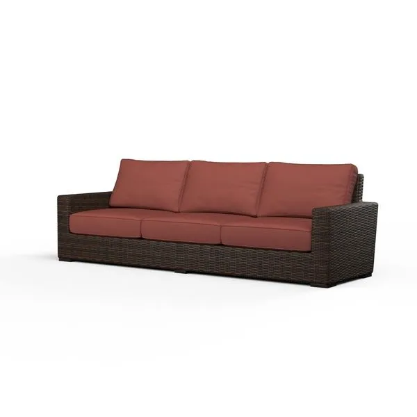 Three-seat outdoor sofa with wide armrests, wrapped in dark cognac multi-color resin wicker with rust-colored cushions
