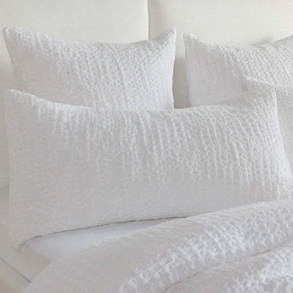 White linen sham with a waffle-like textured weave in a neutral palette on a bedding set