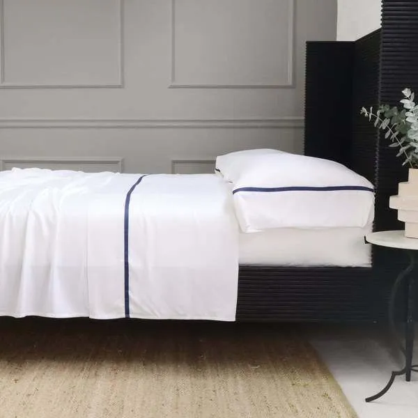 Langston Bamboo Sateen Pillowcase Set of 2 in navy, king-sized with smooth, soft satin finish on a bed
