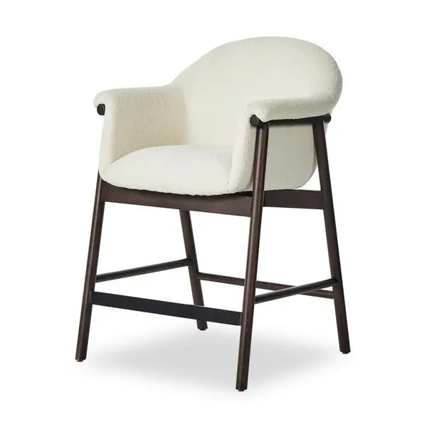 Sora Stool with curved back and armrests, cream boucle upholstery, dark tapered wooden legs and black footrest