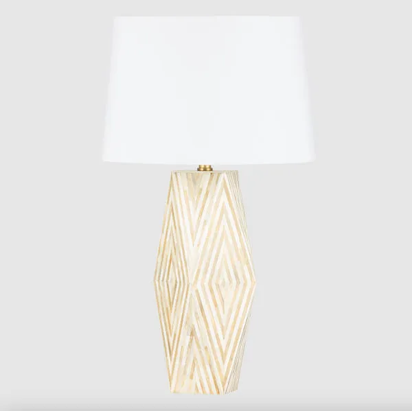 Front view of lamp on beige surface with dark blue background emphasizing its faceted bone inlay base