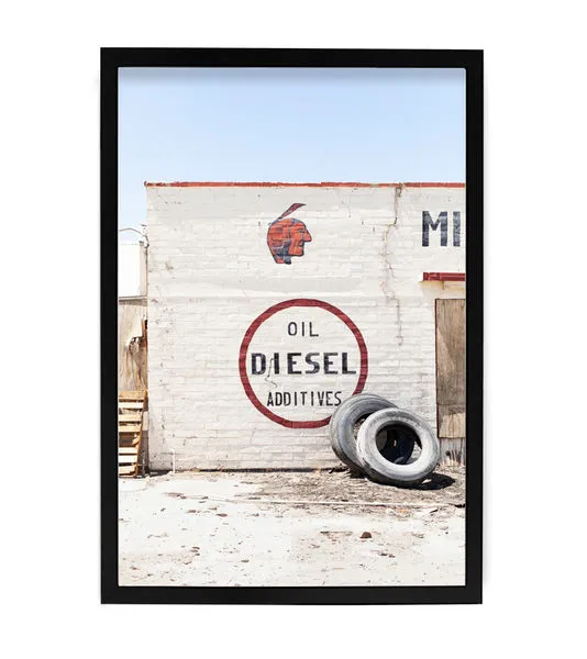 Aerial shot of a white brick wall featuring red lettering with an Indian head and stacked tires in a high desert setting