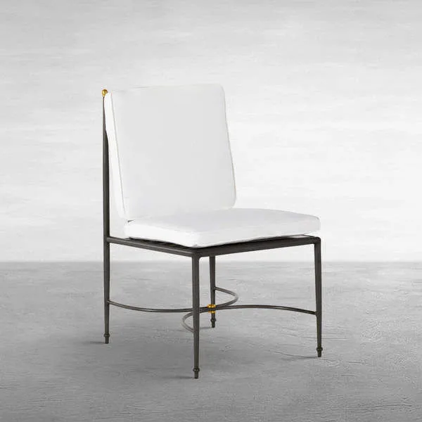 Outdoor side chair with white cushions and wrought aluminum frame featuring subtle gold accents on finials