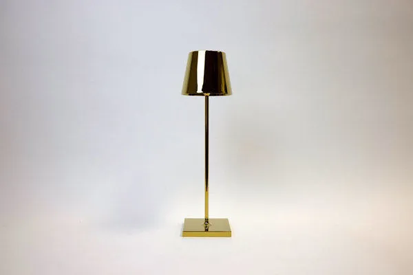 Vera Gold Poldina Pro Table Lamp with sleek gold metal base and cylindrical shade on a square pedestal