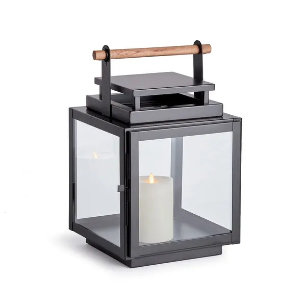Adwin Outdoor Lantern with black square metal frame, wide glass panes, and teak wood handle, candle inside