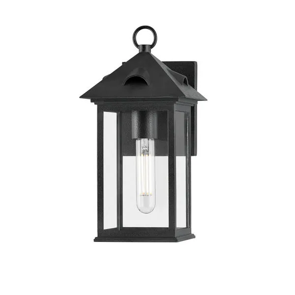 Outdoor wall sconce in forged iron with clear glass panels and single tubular bulb inside a classic lantern design.
