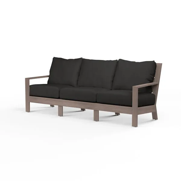 Laguna Sofa with hand-brushed aluminum frame mimicking driftwood, featuring plank arms and curved slat back with black cus...
