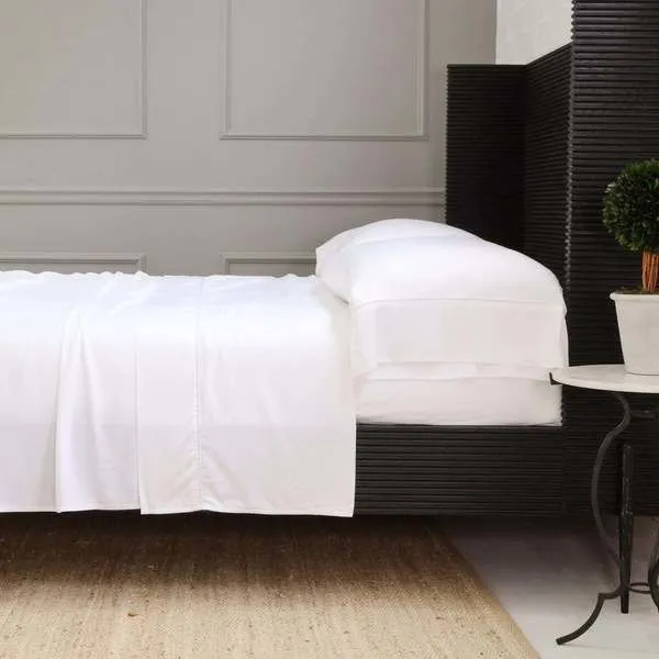 California King Sheena Bamboo Sateen Sheet Set in white on black platform bed with pillows, side table and plant