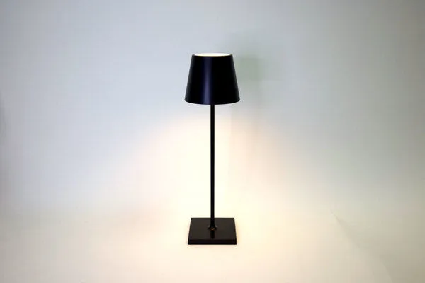 Vera Black Poldina Pro Table Lamp with sleek black metal finish, conical shade, and square base lighting a neutral space