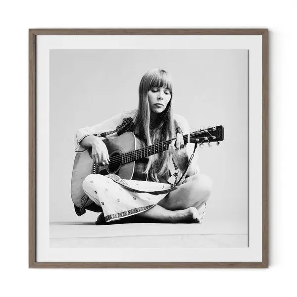 Black and white portrait of Joni Mitchell playing acoustic guitar, seated cross-legged in 1.5 inch rustic walnut frame