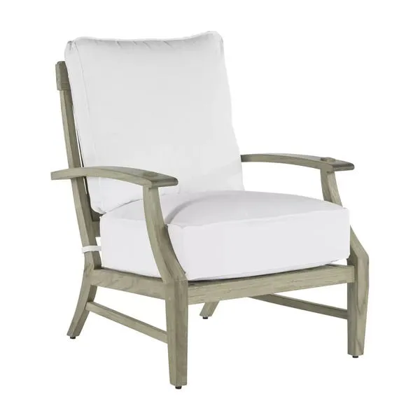 Outdoor lounge chair with teak frame in natural finish and plush white cushions on seat and back