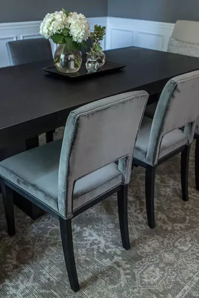 Heirloom Fog Rug with subtle gray and white patterns under a dark wood dining table and velvet gray dining chairs in a lig...