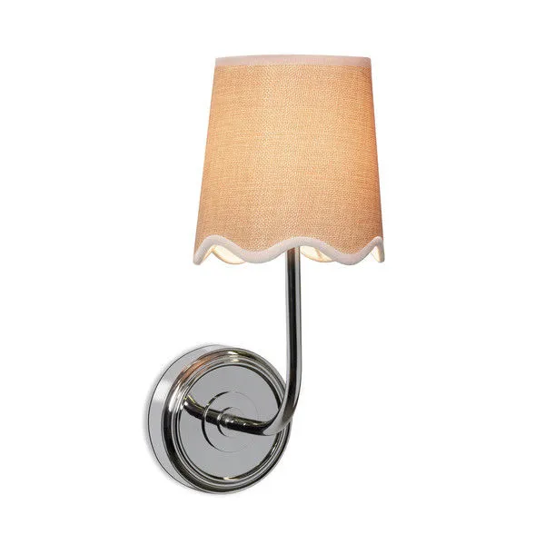 Ariel sconce illuminated, showing warm glow through woven beige lampshade with scalloped edge