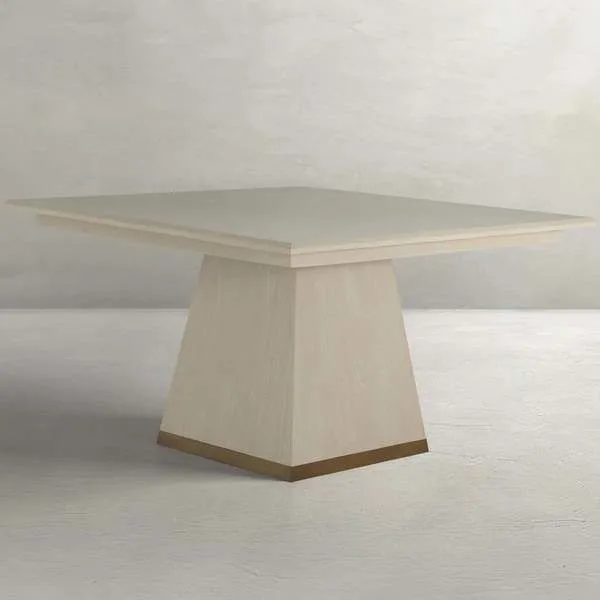 Square dining table with white-cerused veneer finish, angled tapered base, and gold-toned banding at base