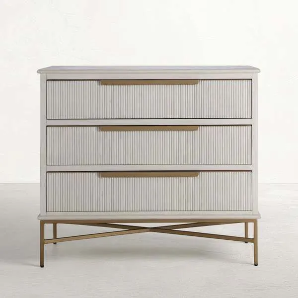 Distressed antique white wood chest with three ribbed drawer fronts and satin brass base in cross design