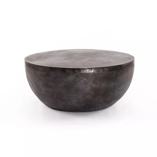 Aged grey aluminum drum coffee table with a smooth round top and curved base, sleek and minimalist design.